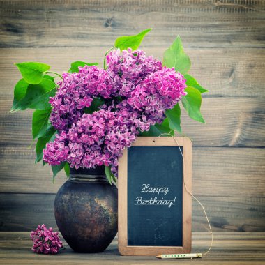 bouquet of lilac flowers. blackboard with text Happy Birthday!