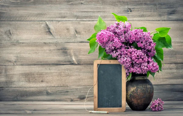 Lilac flowers with blackboard on wooden background — Stock Photo, Image