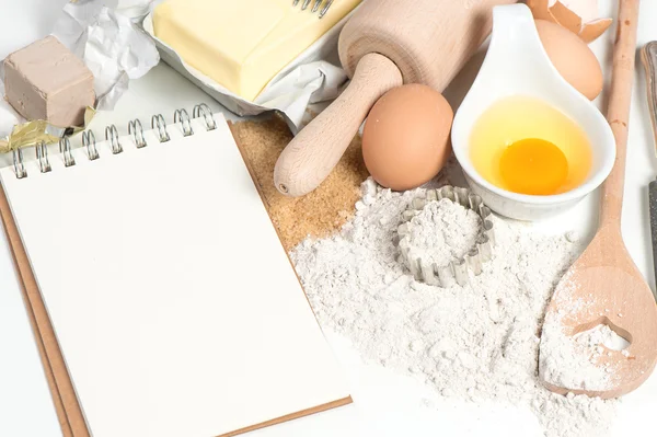 Yemek tarifi kitabı ve pişirme malzemeleri yumurta, un, şeker, tereyağı, y — Stok fotoğraf