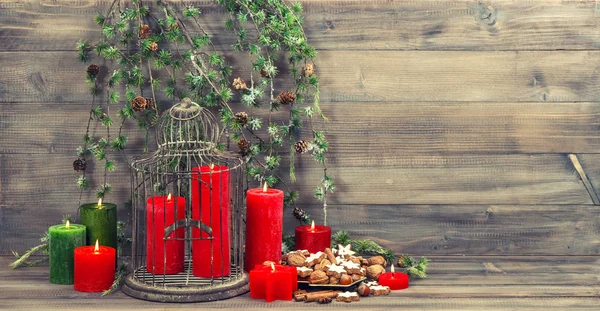 Рождественские украшения с красными свечами, птичьей клеткой и сосновой ветвью — стоковое фото