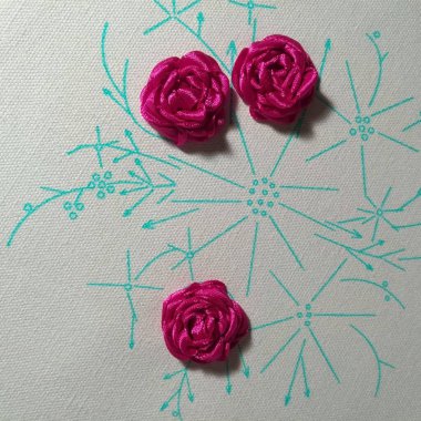 Çiçeklerin pembe gül yaprakları halkadaki nakış işleme şeritlerini şekillendirir. Güllerin nakış dokusunu yakından çek. Hobi tekstil.