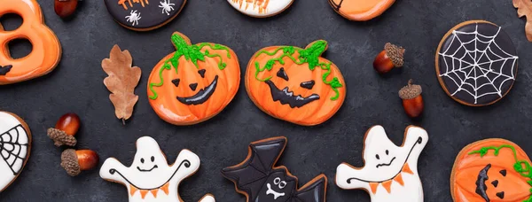 Karanlık taş arka planda komik ve ürkütücü Cadılar Bayramı balkabakları. Cadılar Bayramı partisi için ev yapımı parlak kurabiyeler.