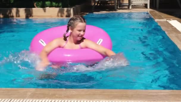 Chica adolescente jugando con anillo inflable rosa en la piscina. Chica salpicando agua y buceando bajo el agua. Movimiento lento — Vídeo de stock