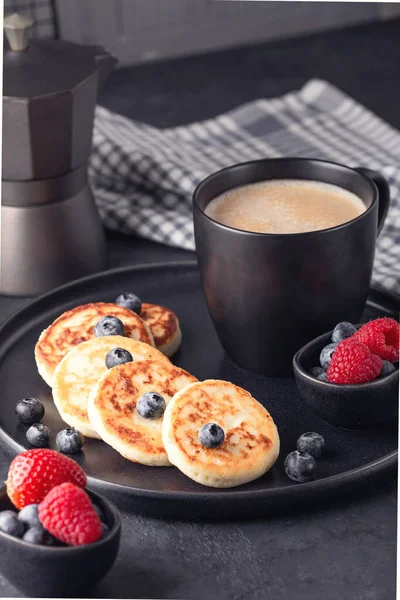 Close up of cheese pancakes with fresh berries on dark ceramic plate. Syrniki. Vertical photo — Stock Photo, Image