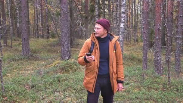 Caucasian man using smartphone to find his location in the forest. Traveler catching a cellular network on a smartphone while walking in the forest — Stock Video