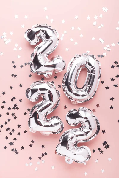 Silver balloons in the form of numbers 2022 and confetti on blue background on pink background. New year celebration — Stock Photo, Image