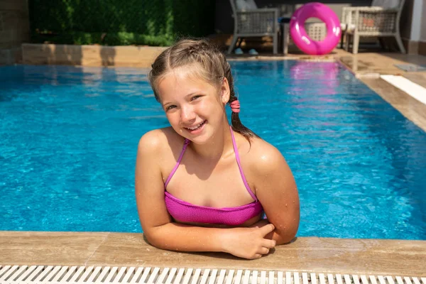 Yüzme havuzunda turkuaz suyla rahatlayan gülümseyen kız. Seyahat ve tatil kavramı