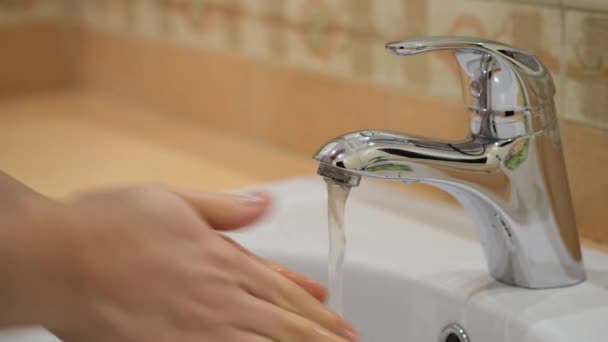 A nő szappannal mossa a kezét otthon a csap alatt.