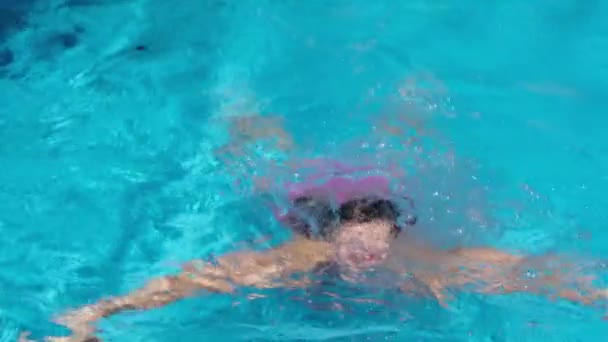 Linda chica en vasos de agua rosa en la piscina. Chica emergiendo del agua — Vídeo de stock