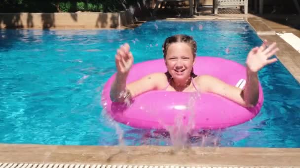 Menina adolescente brincando com anel inflável rosa na piscina. Menina salpicando água. Movimento lento — Vídeo de Stock