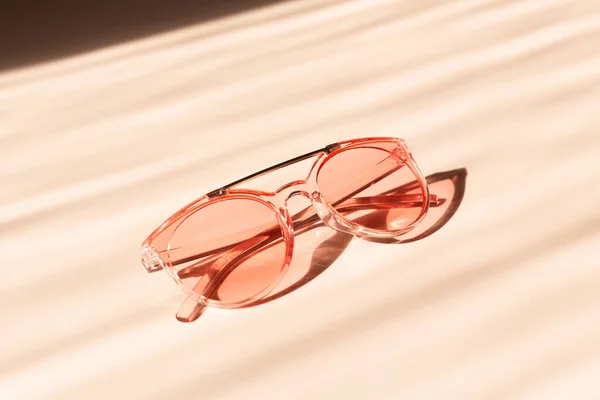 Modne różowe okulary przeciwsłoneczne na beżowym tle. Koncepcja akcesoriów letnich — Zdjęcie stockowe