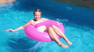 Yüzme havuzunda pembe şişme yüzükte yüzen kız. Seyahat ve tatil kavramı