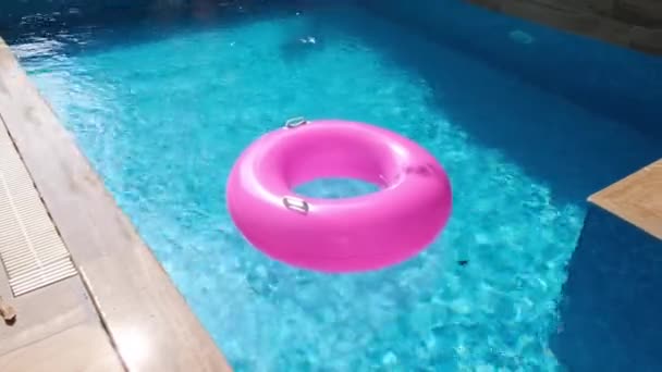 Różowy pompowany pierścień w pustym basenie. Odświeżająca niebieska woda. Nikt. — Wideo stockowe