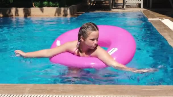 Klein schattig meisje spelen met roze opblaasbare ring in het zwembad. Zomer reizen hotel vakantie — Stockvideo