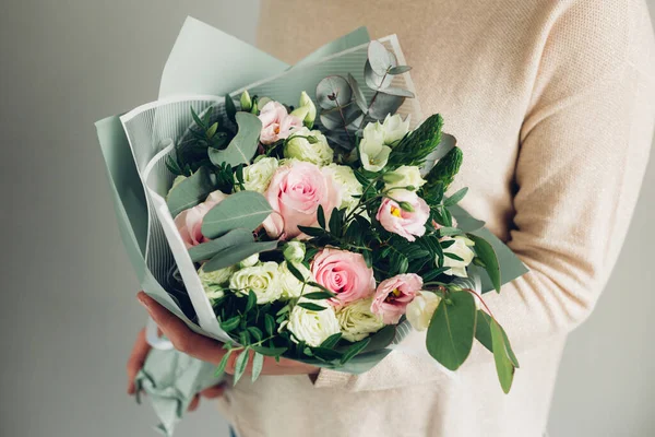 Woman holding fresh blossoming flower bouquet of beautiful flowers in pastel pink colour Stock Image