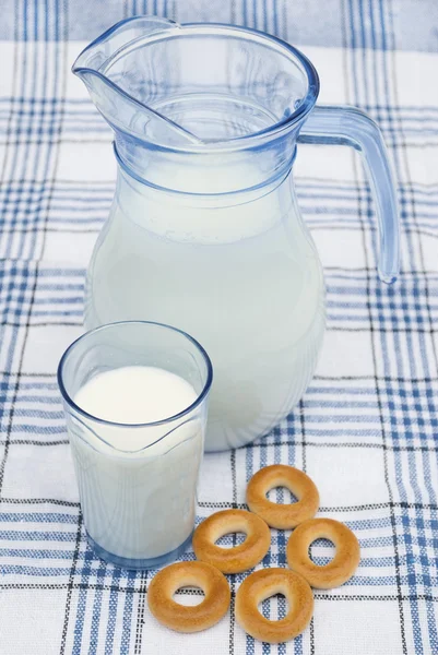 Milch in Krug und Glas mit Bagels auf Tischdecke — Stockfoto