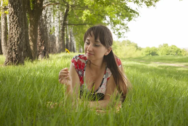 Fille couchée sur l'herbe avec une fleur dans la main — Photo