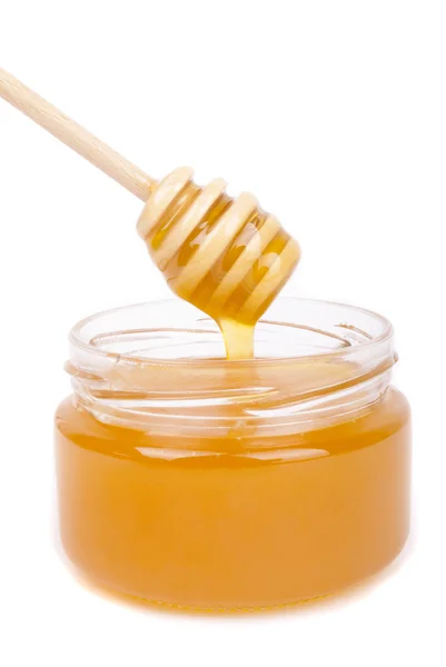 Honey dripping into a jar with a special spoon. Royalty Free Stock Images