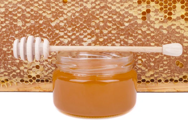 Jar of honey and wooden spoon on a background honeycombs. — Stock Photo, Image