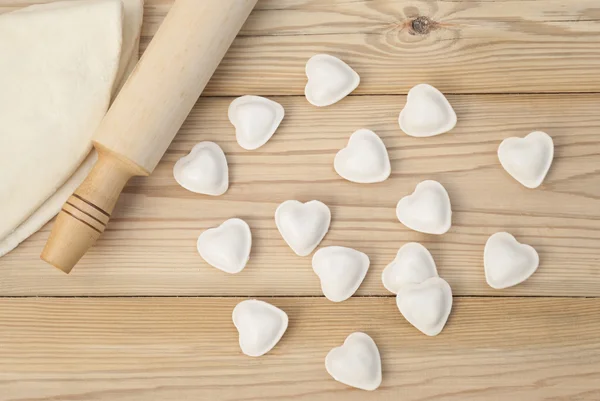 Dumplings in a heart shape dough and rolling pin. — Stock Photo, Image