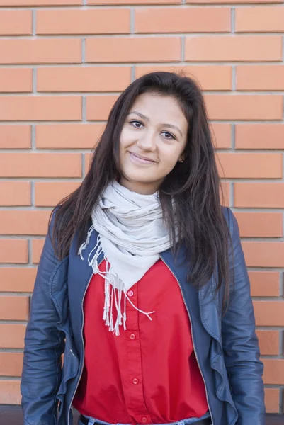 Attractive young girl standing against a brick wall. — Stock Photo, Image