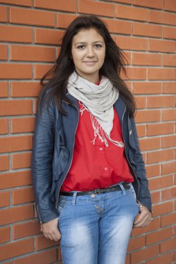 Genç bir kız arka planda duruyor bir tuğla duvar.
