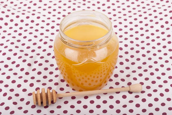 La miel en el frasco de cristal sobre el mantel . —  Fotos de Stock