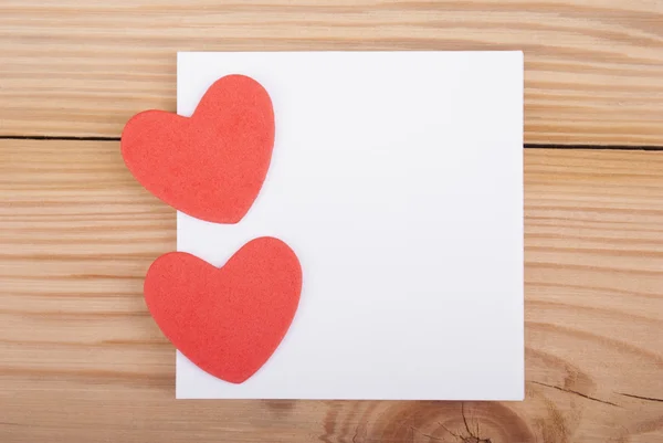 Δύο καρδιές και χαρτί σε ξύλινο φόντο. — Φωτογραφία Αρχείου