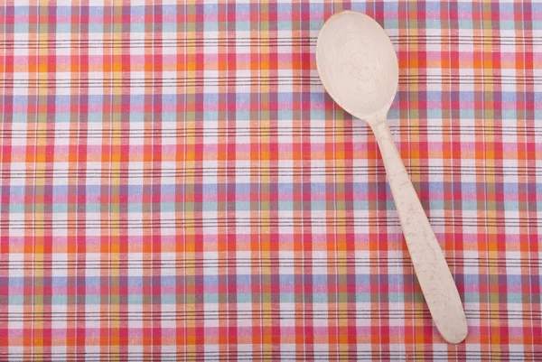 Wooden spoon on checkered tablecloth. — Stock Photo, Image