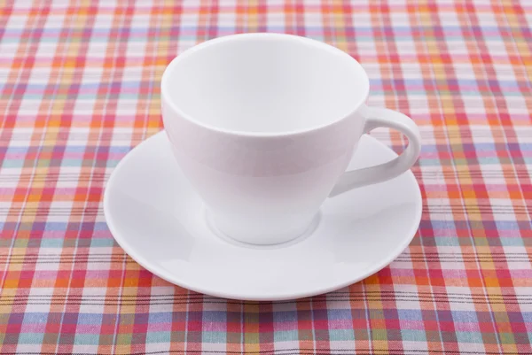 Kaffeetasse auf karierter Tischdecke. — Stockfoto