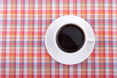 Kareli masa örtüsü üzerinde bir fincan kahve..