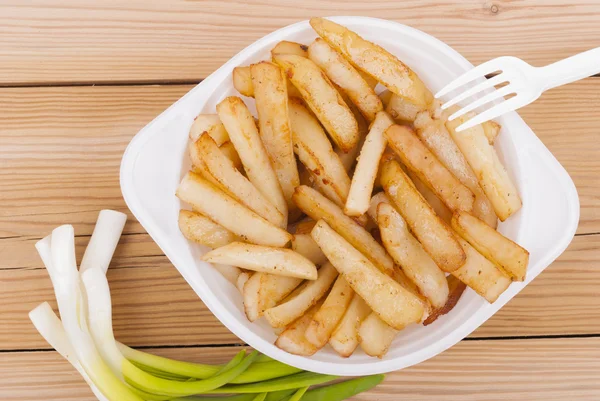 Batatas fritas com cebolas em uma mesa de madeira . — Fotografia de Stock