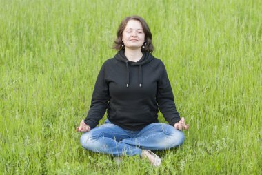 kadın parkta yeşil çim üzerinde lotus olarak meditasyon.