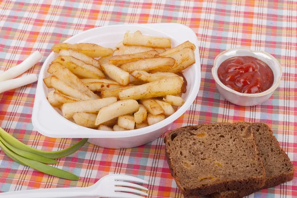 Batatas fritas em uma chapa em uma toalha de mesa . — Fotografia de Stock