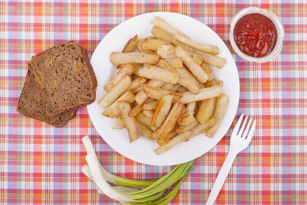 Pommes de terre frites dans une assiette sur une nappe . — Photo