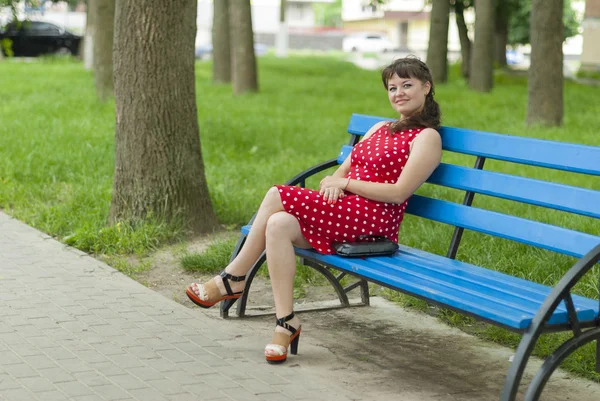 Mooi meisje op een bankje in het park. — Stockfoto