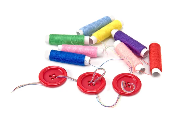 Red buttons and thread spools on white background — Stock Photo, Image