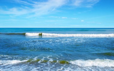 Sabah gökyüzünün önü açık beyaz bulutlarla parlak mavi. Ve gün ışığında okyanus derin çivit mavisi. Sakinim, sakinim, rahatım. Soğuk arkaplan fikri ve üste boşluk kopyalama.
