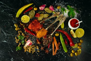 Karanlık bir masada bir sürü farklı baharat ve aromatik otlar. Yukarıdan görüntüle.
