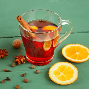 Ahşap bir masada sıcak şarap, portakal ve baharatlar..