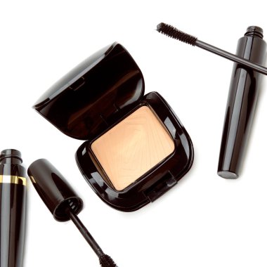 Beyaz arkaplanda yüz pudrası ve rimel izole edilmiş..