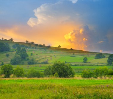 Samanlıkları ve samanlıkları olan resimli tepeler. Akşam manzarası.