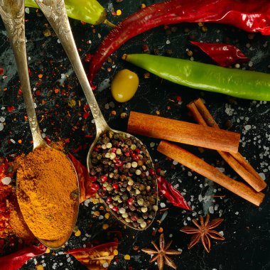 Karanlık bir masada bir sürü farklı baharat ve aromatik otlar. Yukarıdan görüntüle.