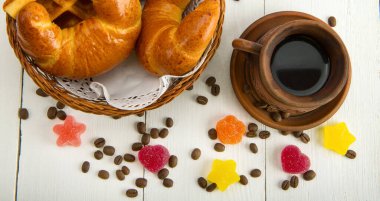 İçinde kahve, kruvasan ve waffle olan klasik bardaklar ve beyaz arka planda diğer tatlılar..