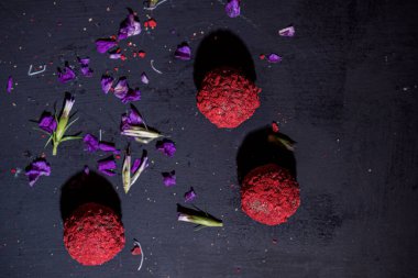 Çiçek yapraklı, siyah bir levhada kırmızı soğutulmuş çikolatalar, yakın çekim, görüş açısının üstünde.