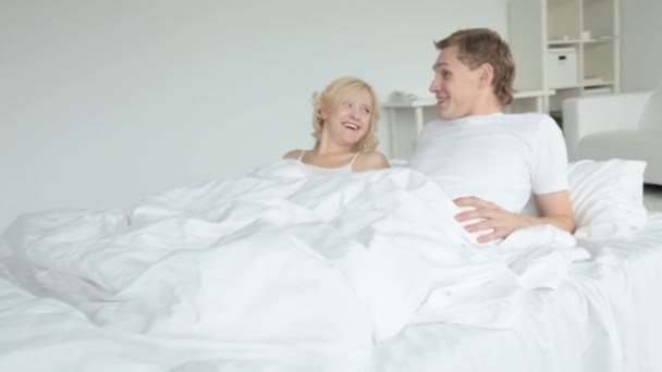 Пара, лежащая в постели и болтающая — стоковое видео