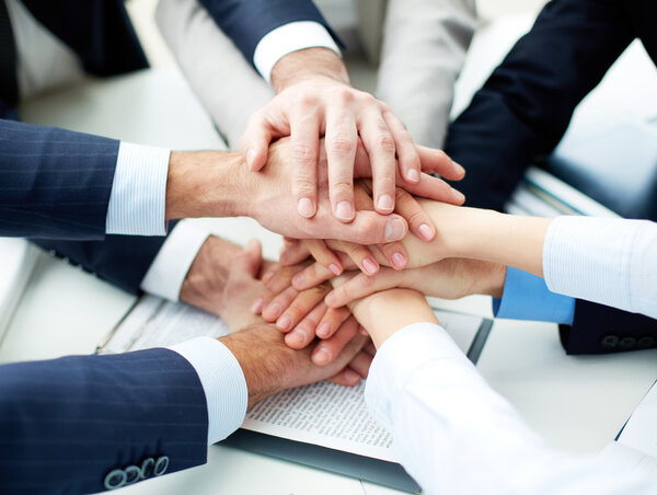 business partners making pile of hands at meeting