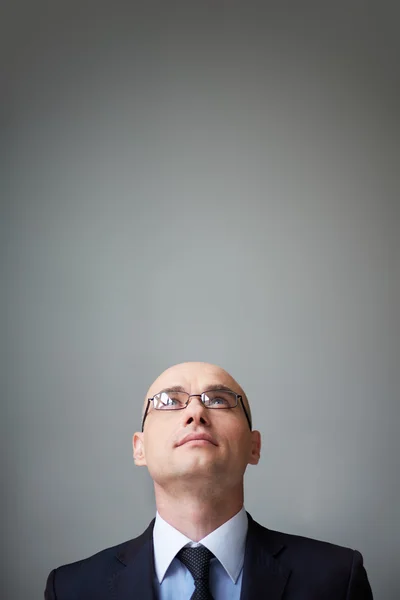 Businessman in eyeglasses looking upwards — Stock Photo, Image