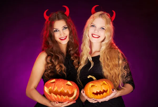 Heksen met horens en halloween pompoenen — Stockfoto