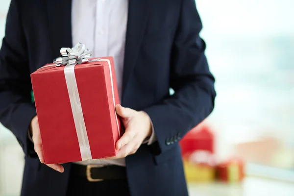 Empresário segurando presente em caixa de presente vermelha — Fotografia de Stock